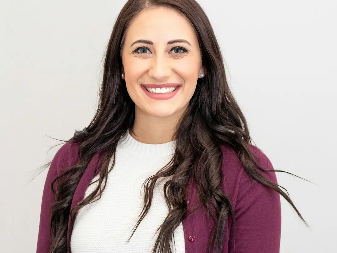 A smiling woman in a burgundy cardigan