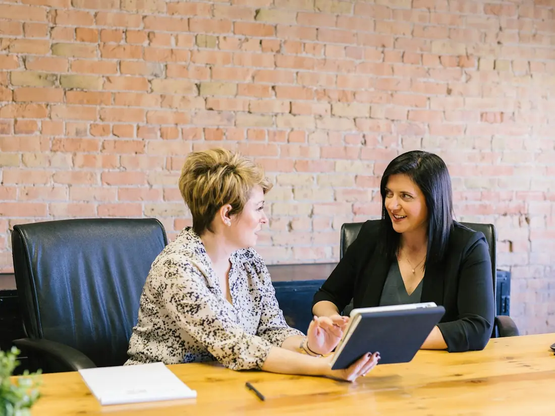 Two women reviewing a tablet at a conference table