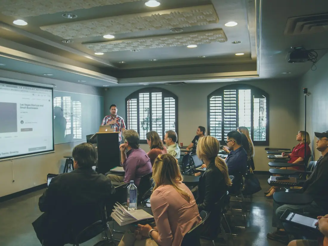A presenter speaking to a seated group in a meeting room