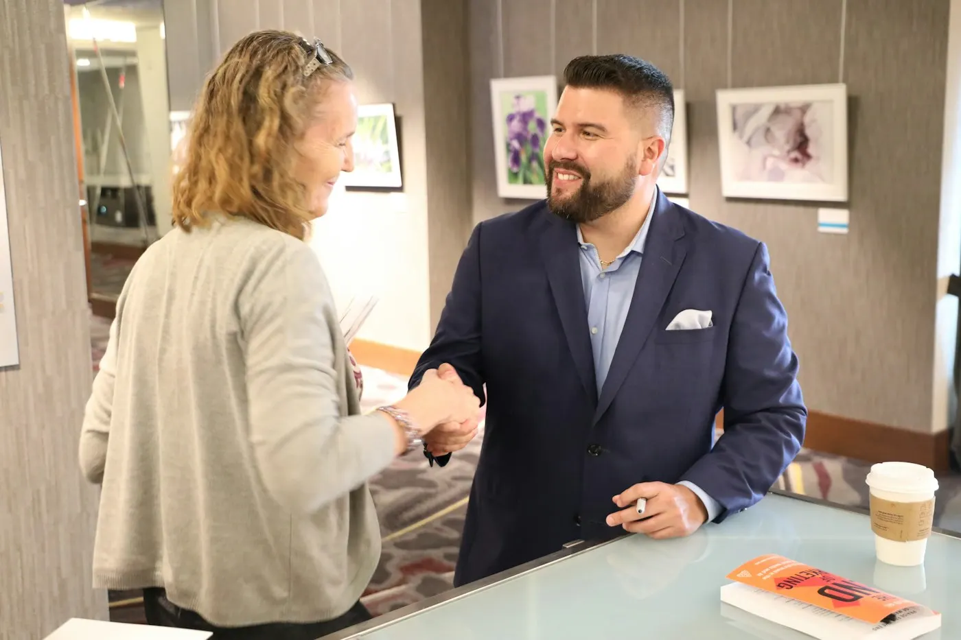 A buyer and a seller shaking hands across a desk